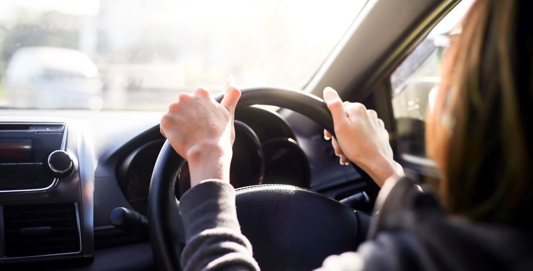 Frau im Auto mit den Händen am Steuer